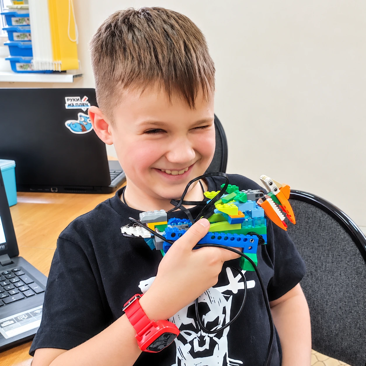 Ученик с красными часами показывает LEGO-дракона