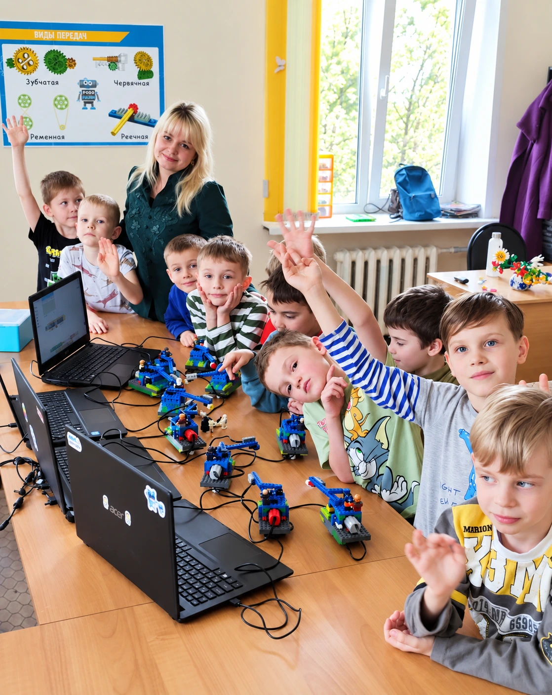 Преподаватель и большая группа учеников вокруг стола с ноутбуками и роботами