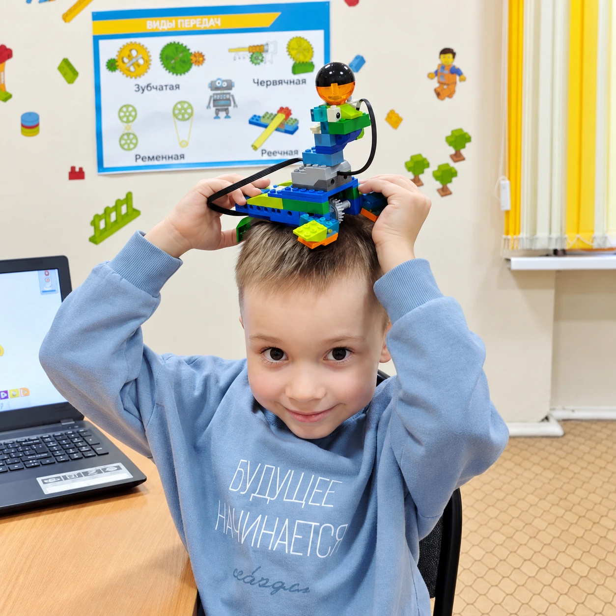 Ученик курса «Робототехника для супергероев» держит собранную LEGO-модель над головой