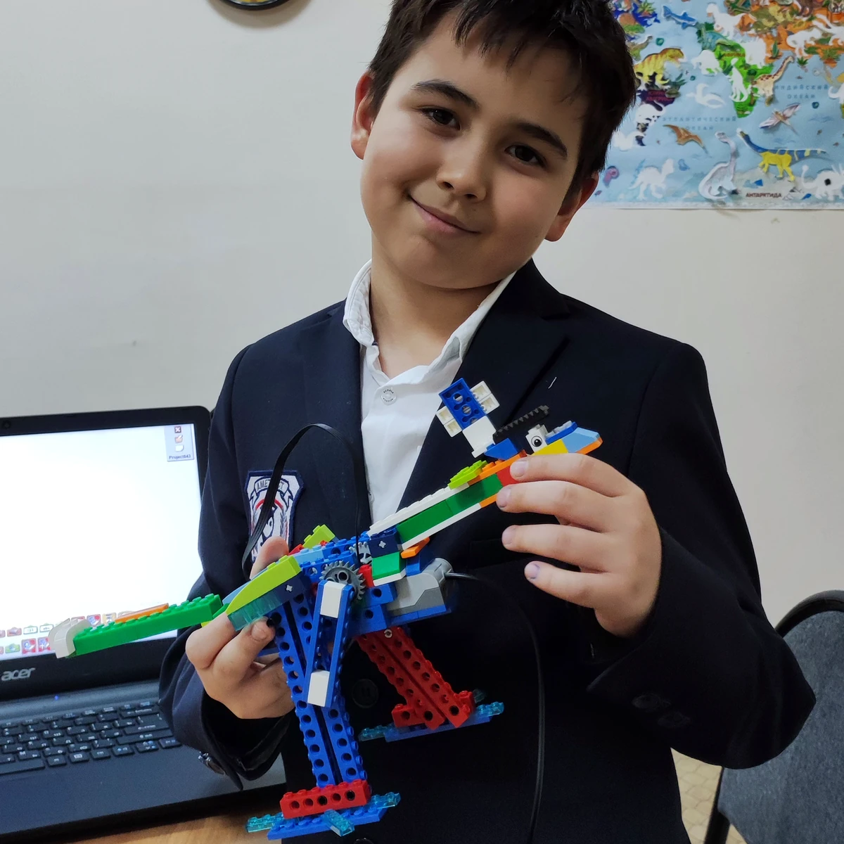 Ученик показывает собранную модель динозавра LEGO
