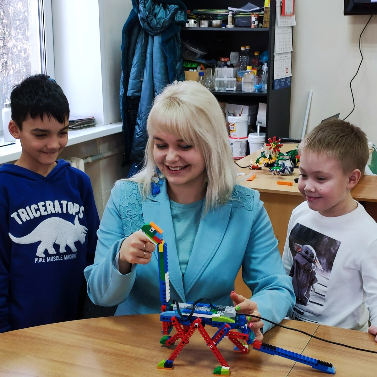 Преподаватель и ученики с подвижной моделью динозавра LEGO
