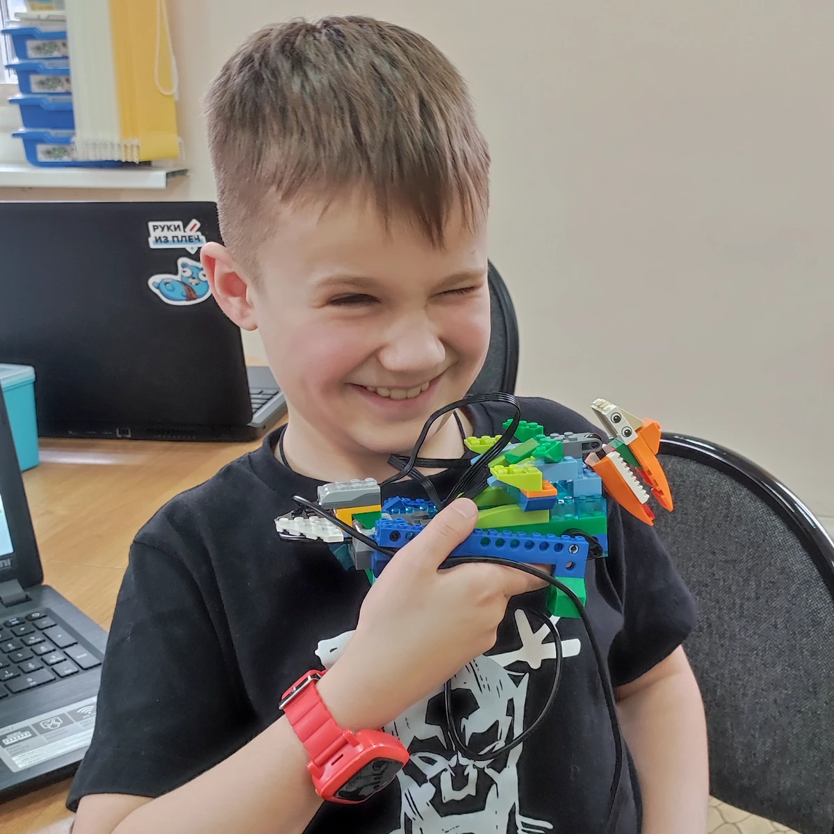 Ученик с красными часами показывает LEGO-дракона