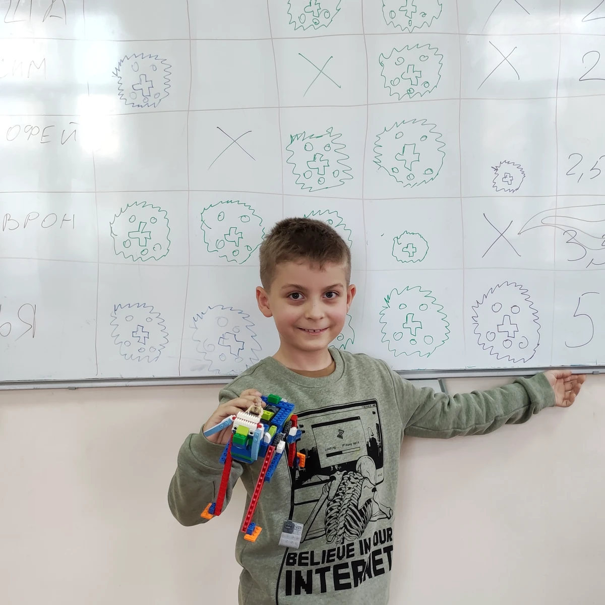 Ученик показывает динамическую модель на длинных красных опорах у доски